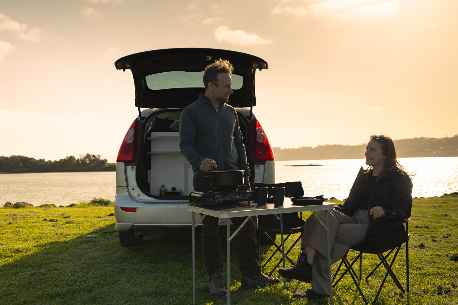 Camp mit Tisch und Stühlen am Heck des Medium Budget Campers