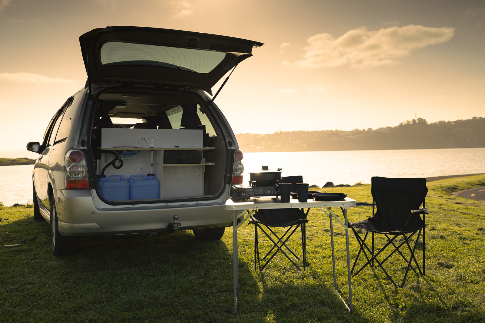 Geöffnetes Heck des Medium Premium Campers mit Küche und Campingstühlen